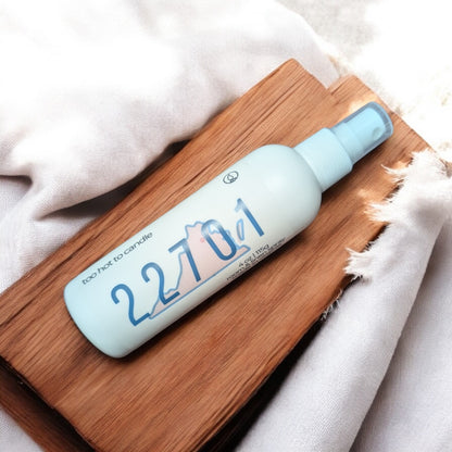 A spray bottle with the label 22701, placed on a wooden surface, with a white and blue color scheme.