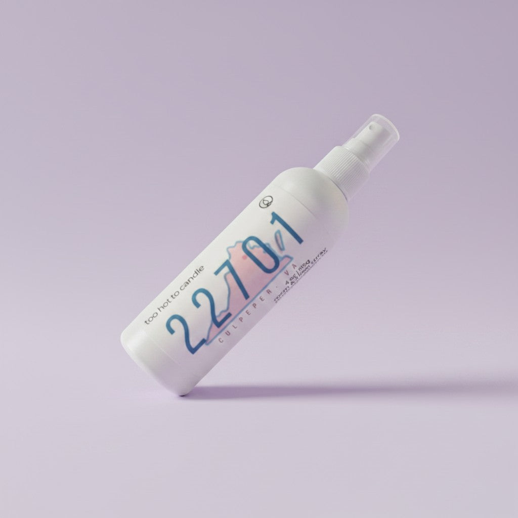 A white spray bottle labeled '22701' with blue and pink graphic details, photographed diagonally on a solid light purple background.